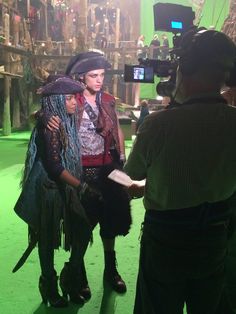 two people dressed in pirate costumes standing next to each other on a green carpeted floor