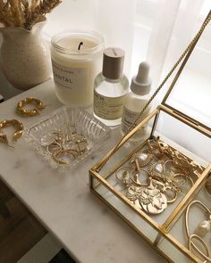 a table topped with lots of gold jewelry and bottles filled with lotion sitting on top of it