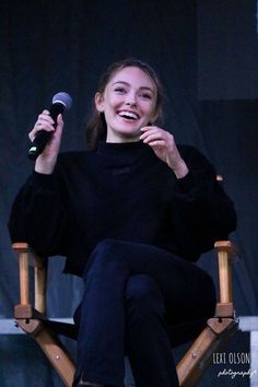 a woman sitting in a chair holding a microphone