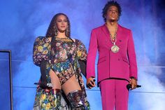 two people standing next to each other in front of a blue background wearing bright outfits