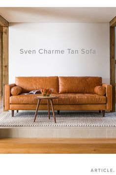 a brown leather couch sitting on top of a wooden floor next to a white wall