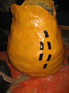 a large orange plastic bag sitting on top of a pile of trash bags with faces drawn on it