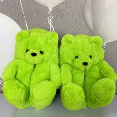 two green teddy bears sitting next to each other with white balloons in the air behind them