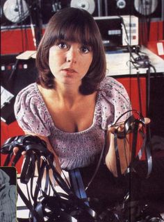 a woman sitting on top of a bike in a room filled with electronics and equipment