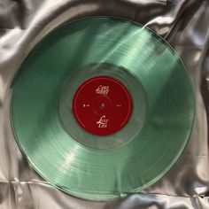 a green vinyl record sitting on top of a silver sheet