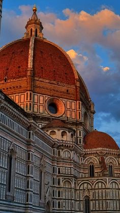 the dome of an old building with a clock on it's side and clouds in the background