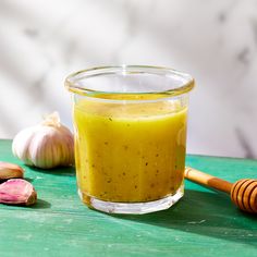 a glass jar filled with yellow liquid next to garlic