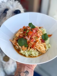 a person holding a white bowl with food in it