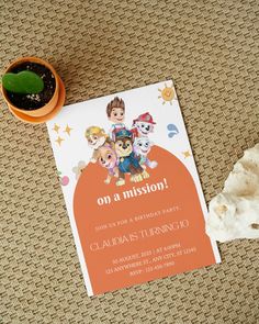 an orange birthday party card sitting on top of a table next to a potted plant