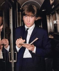 a man in a suit and tie holding a piece of paper while standing next to an open door