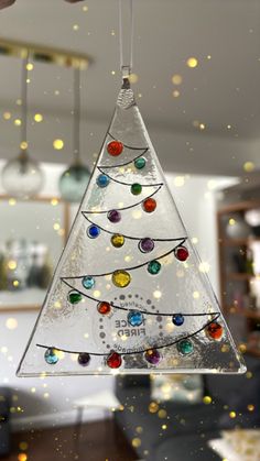 a glass christmas tree ornament hanging from a ceiling