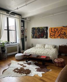 a living room filled with furniture and paintings on the wall next to a wooden floor