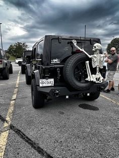 a jeep with a skeleton on the front is parked in a parking lot while people look at it