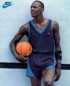 a man holding a basketball standing next to a wall