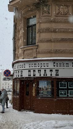 people are standing outside in the snow near a building with an advertisement on it's side