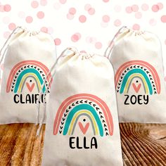 two drawstring bags with personalized name and rainbow design on them sitting on a wooden table