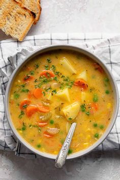 a bowl of soup with carrots, potatoes and parsley in it next to a slice of bread