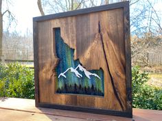 a wooden frame with an image of two birds flying over the mountains and trees in the background