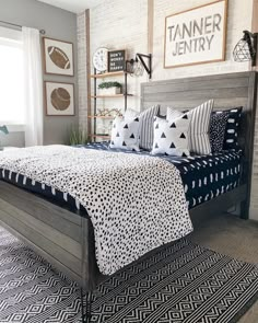 a bed with black and white pillows on top of it next to a brick wall