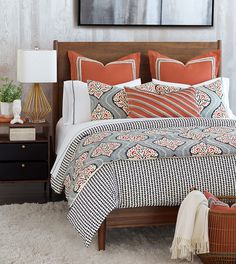 a bed with an orange and white comforter on top of it next to a night stand