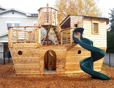 a wooden playset with a slide and play house in the back ground next to it