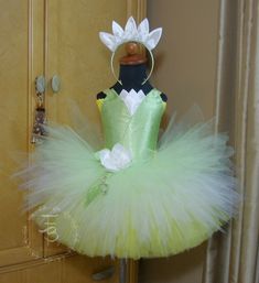 "Princess Tiana Dress Set includes: - dress - headpiece \"Princess Collection\"....Our Princess Tiana inspired tutu dress is absolutely gorgeous. Skirt is made of 4 layers of premium quality made in the USA tulle that's hand tied onto bodice. Dress is made to best mimic Princess Tiana's gown. Bottom two layers are yellow and cut across. Third layer is white, cut at an angle to mimic Tiana's gown petals that hang just past gown hem. Fourth layer in mint green is shorter than third layer and cut a Tiana Costume Diy, Princess Tiana Tutu, Children Vision Board, Peacock Party Decorations, Bday Dress Ideas, Tutu Party Decorations, Princess Tiana Dress, Princess And The Frog Party, Princess Tiana Birthday Party