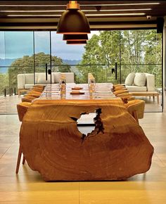 a large wooden table with chairs around it in a living room next to a glass wall