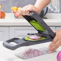 a person using a vegetable slicer on top of a counter with onions in it