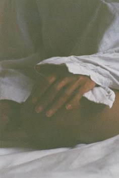 a person laying in bed with their hands on top of each other's stomach