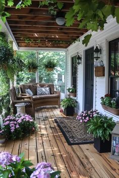 a porch with flowers and plants on the wooden floor, along with two wicker couches