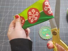 a person holding a pair of scissors in front of a green bag with snowflakes on it