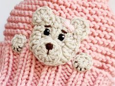 a crocheted teddy bear laying on top of a pink blanket