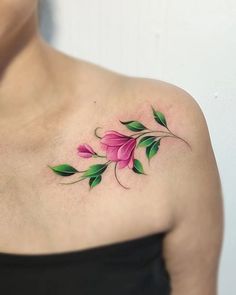 a woman's shoulder with pink flowers and green leaves