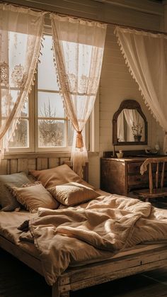 a bed sitting under a window next to a dresser and table with a mirror on top of it