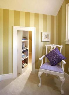 a white chair sitting in a room next to a book shelf