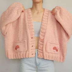 a woman is wearing a pink cardigan with mushrooms on the front and back pockets