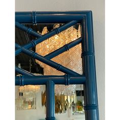 a decorative mirror with blue frame and glass chandelier hanging from it's ceiling