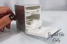 a hand holding a miniature model of a dishwasher in it's box