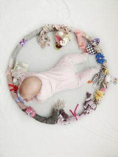 a baby laying on its back surrounded by stuffed animals and other toys in a circle