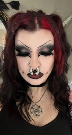 a woman with red hair and black makeup is wearing a nose ring, nose piercings on her nose