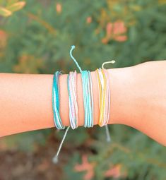 a woman's arm with several different colored bracelets on top of each other