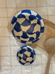 two blue and white bowls sitting next to a wooden spoon on top of a table