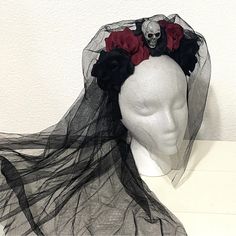 a white mannequin head wearing a black veil with red roses on the top