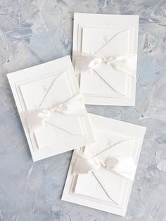 three white cards with bows on them