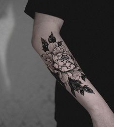 a black and white flower tattoo on the left upper half of the arm is shown