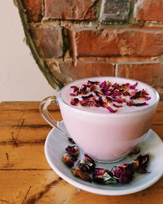 a cup filled with pink liquid sitting on top of a saucer next to a brick wall