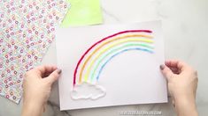 someone is making a rainbow card with crayons and glue on the paper to make it