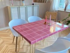 a pink table with white chairs around it