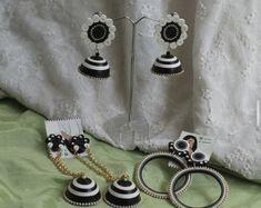 two black and white jewelry pieces on a green tablecloth next to a pair of earrings