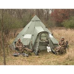 two men sitting in chairs next to a tent